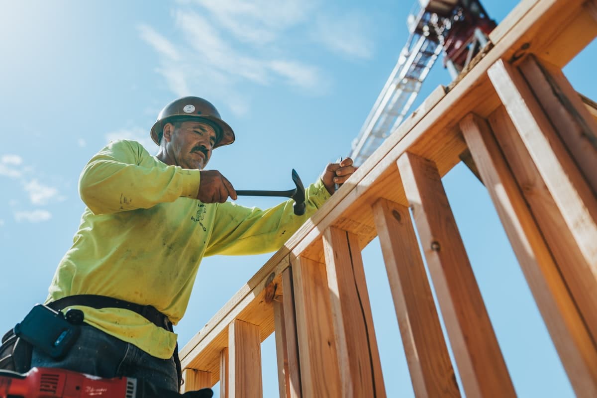 Licensed contractor framing a home under a blue sky